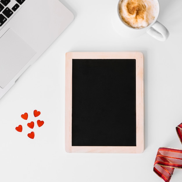 Harten en schoolbord in de buurt van laptop en koffie