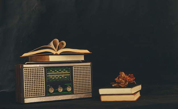 Hartvormige boeken geplaatst op retro-radio-ontvangers met gedroogde bloemen erop