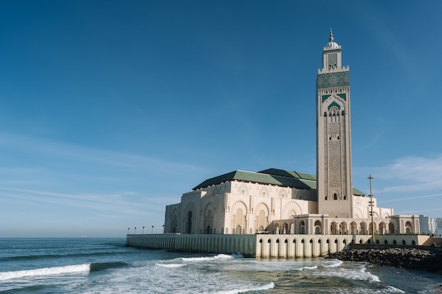 Hassan II-moskee omgeven door water en gebouwen onder een blauwe lucht en zonlicht