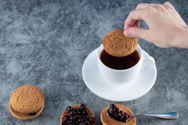 Havermoutkoekjes met zwarte bessen confiture geserveerd met een kopje thee