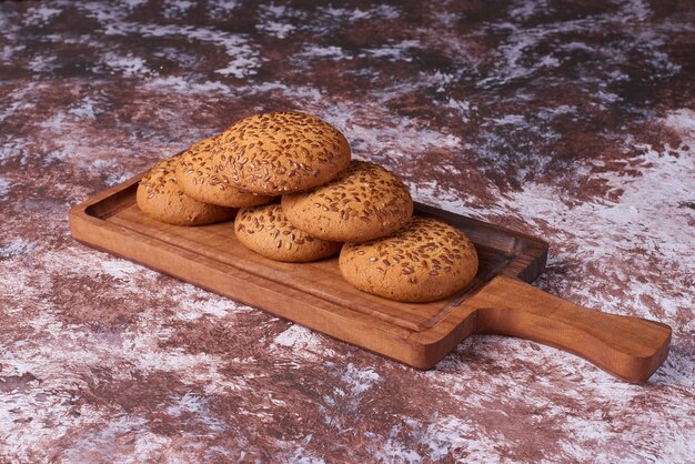 Havermoutkoekjes met zwarte komijn op een houten schaal over het marmer.