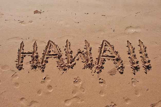 Hawaii geschreven in het zand op het strand
