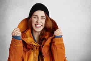 Gratis foto headshot van aantrekkelijke jonge blanke vrouw met charmante glimlach, gekleed in trendy winterkleren