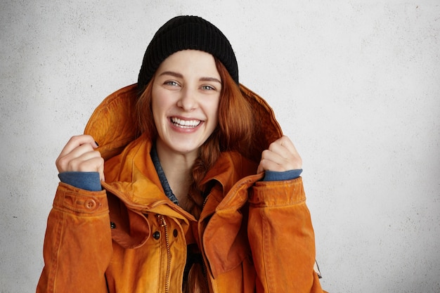 Headshot van aantrekkelijke jonge blanke vrouw met charmante glimlach, gekleed in trendy winterkleren