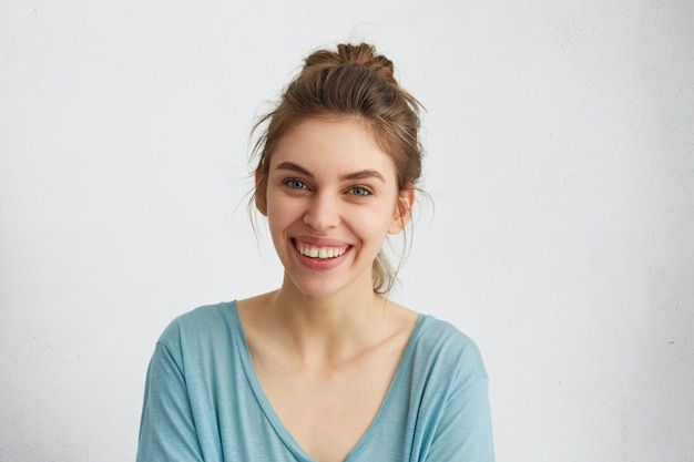 Gratis foto headshot van leuke vrouw met lichtgevende blauwe ogen, gloeiend gezicht en zachte glimlach die zich verheugt over haar succes.