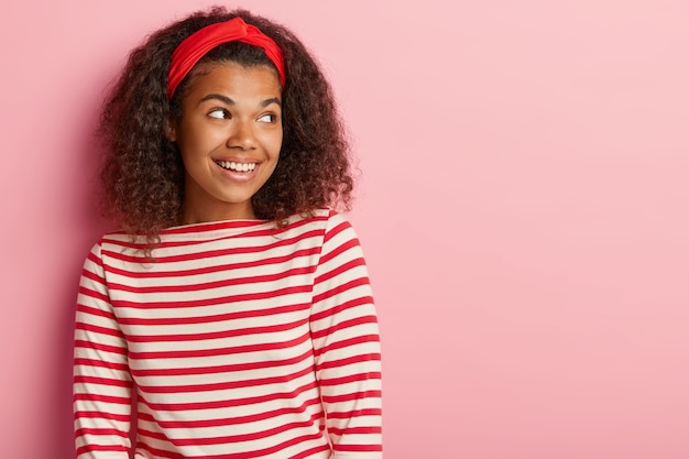 Headshot van mooie tiener met krullend haar poseren in gestreepte rode trui