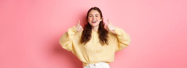 Heel goed, goed gedaan glimlachend meisje dat ondersteunend lacht en duimen laat zien in goedkeuring zoals aw