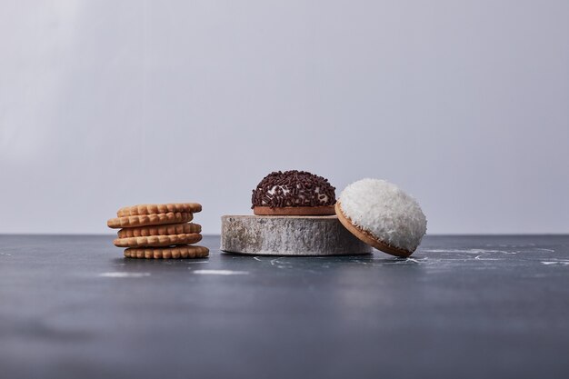 Heemstkoekjes met chocolade en kokospoeder op een stuk hout op blauw.