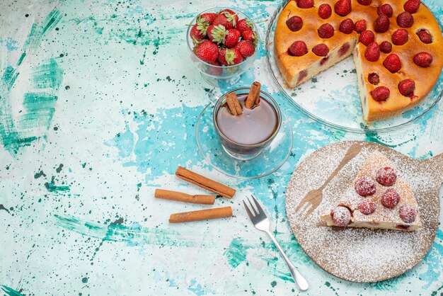 heerlijke aardbeientaart in plakjes gesneden en hele heerlijke cake suiker gepoederd met thee op helderblauwe, bessentaart zoet gebakken deeg thee