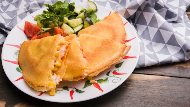 Heerlijke cake dichtbij plantaardige salade op plaat