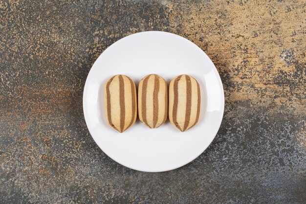 Heerlijke chocolade gestreepte koekjes op witte plaat.