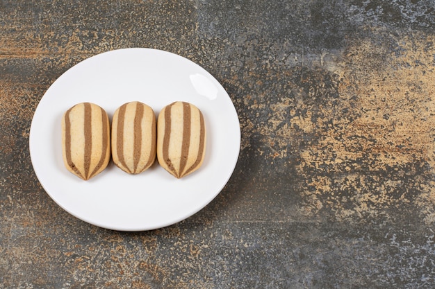 Heerlijke chocolade gestreepte koekjes op witte plaat.