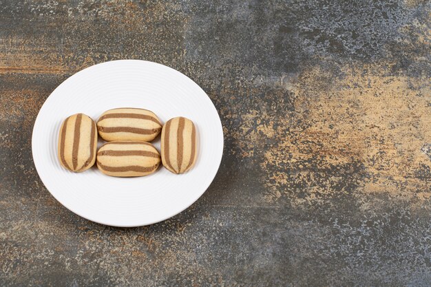 Heerlijke chocolade gestreepte koekjes op witte plaat.