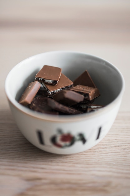 Gratis foto heerlijke chocoladestukjes in de kom op houten bureau