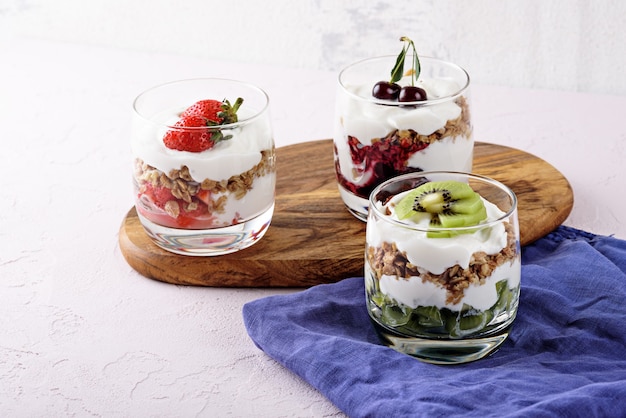 Heerlijke en gezonde desserts met ricotta, muesli, aardbeien, kersen en kiwi op een houten bord