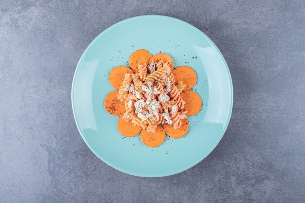 Heerlijke fusilli pasta en wortel op blauw bord.