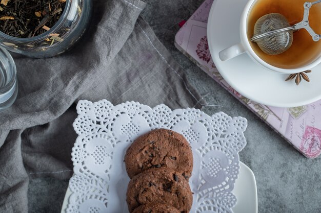 Heerlijke gebakjes met kopje thee op grijs tafelkleed.