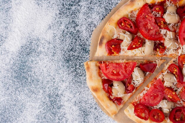 Heerlijke kippenpizza met tomaten op marmer.