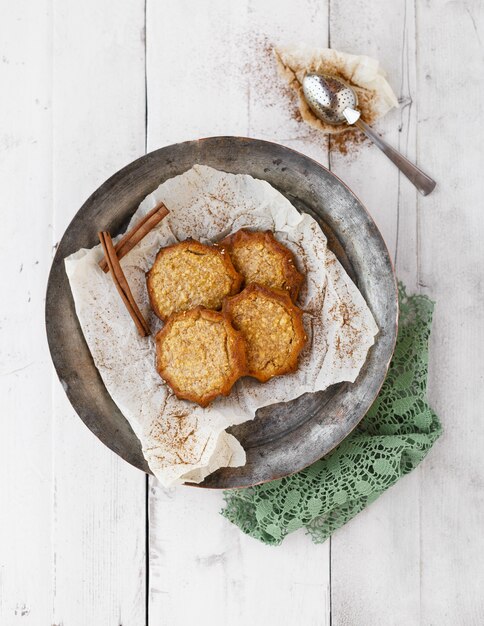 Heerlijke koekjes met kaneel in een metalen kom en een lepel op een witte houten oppervlak