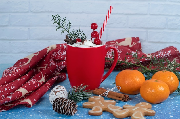 Gratis foto heerlijke peperkoekkoekjes, tangeriens en rode kop koffie op blauw.