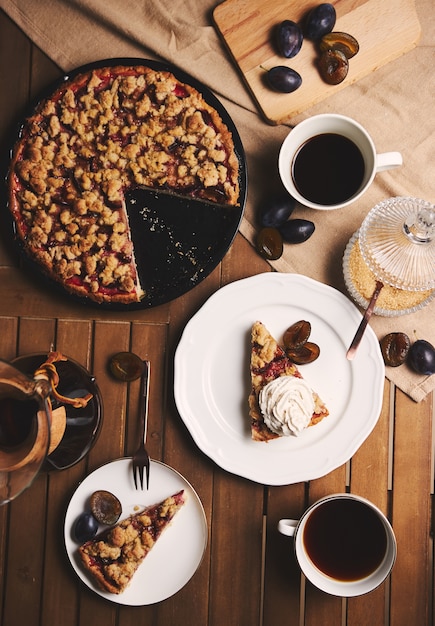 Heerlijke pruimtaart met Chemex-koffie en ingrediënten met stof op een houten lijst met stof