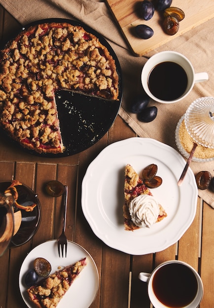 Heerlijke pruimtaart met Chemex-koffie en ingrediënten met stof op een houten lijst met stof