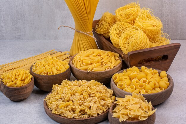 Heerlijke rauwe pasta en macaroni op houten kommen