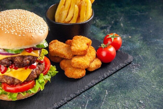 Heerlijke sandwich en kipnuggets friet op een donkere kleurschaal aan de rechterkant op een zwarte ondergrond
