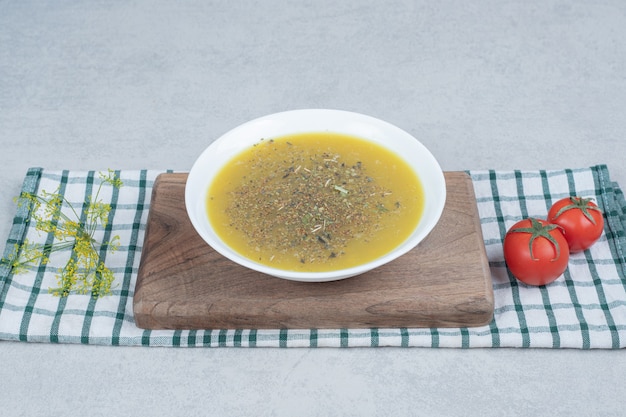 Heerlijke soep met greens en twee tomaten op tafellaken