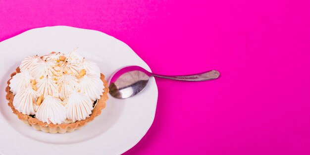 Heerlijke taartjes met meringue op witte plaat tegen roze achtergrond