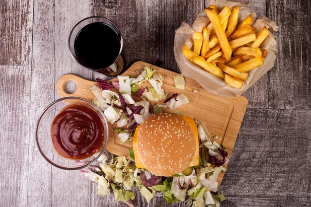 Heerlijke zelfgemaakte hamburgers op houten bord naast friet en cola. Fast food. Ongezond tussendoortje