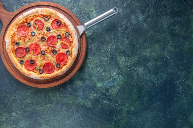 Heerlijke zelfgemaakte pizza op een houten snijplank aan de rechterkant op een donkere ondergrond