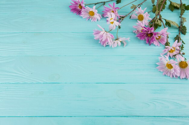 Heldere bloemen verspreid over een blauwe houten tafel.