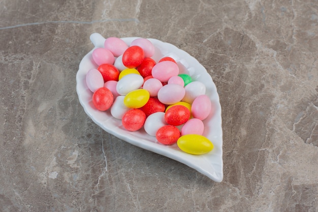 Gratis foto heldere kleurrijke jellybeans in de kleuren rood, groen, roze, blauw, geel en wit. op witte plaat.