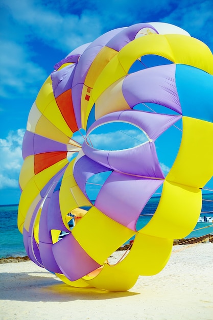 heldere kleurrijke Rainbow Parachute op het strand achter blauwe oceaanwater