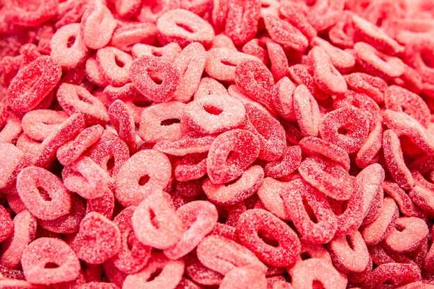 Heldere rode achtergrond met krullende gummy gummy snoepjes