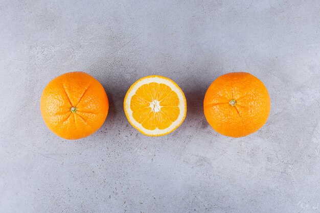 Hele en gesneden oranje vruchten op stenen tafel.