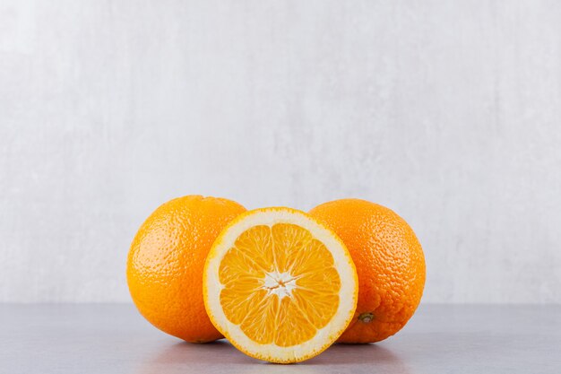Hele en gesneden oranje vruchten op stenen tafel.