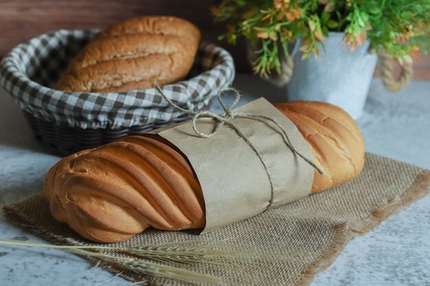 Hele zelfgebakken brood vastgebonden met touw op stenen oppervlak.