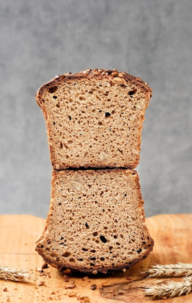 Helften van donkere tarwe - roggebrood op een snijplank. volkoren heerlijk brood met zaden. natuurlijk gefermenteerd zelfgemaakt gezond brood