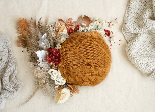 Herfst stilleven met bloemen en gebreide elementen op een witte ruimte close-up.