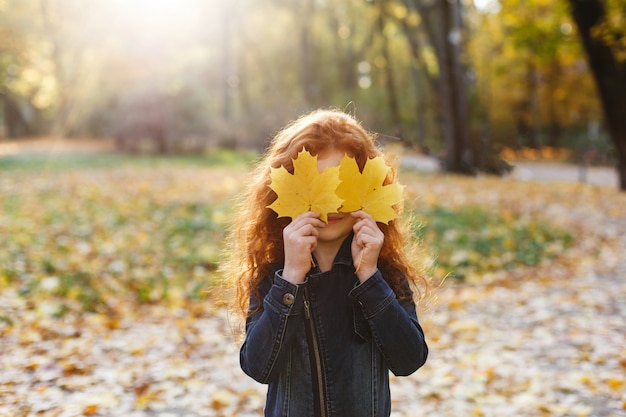 Herfstvibe, kindportret. Het charmante en rode haarmeisje kijkt gelukkig lopend en spelend op t