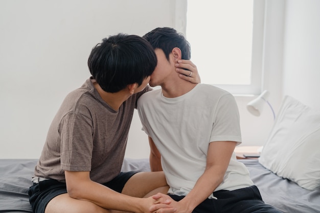 Het Aziatische Vrolijke paar kussen thuis op bed. Jonge Aziatische LGBTQ + mannen gelukkig ontspannen rust samen doorbrengen romantische tijd na wakker worden in slaapkamer thuis in de ochtend.