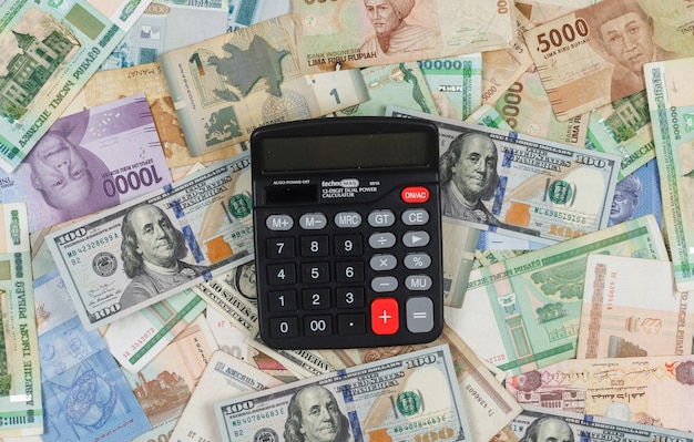 Het bedrijfs en financiële concept met calculator op stapel van geldvlakte als achtergrond lag.