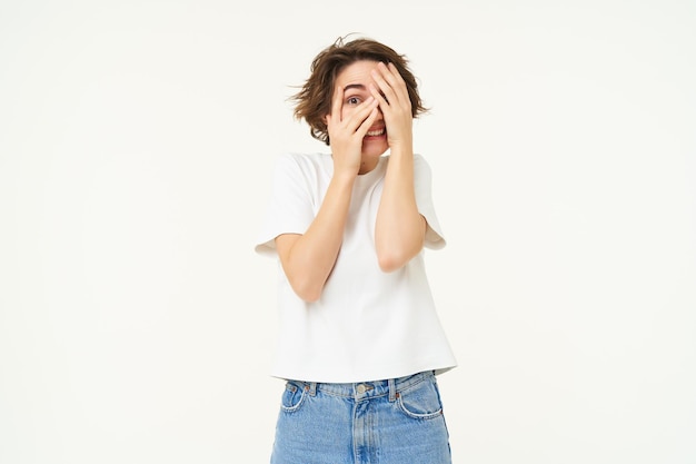 Het beeld van een bange of beschaamde vrouw bedekt haar ogen en gluurt door vingers die bang zijn om naar te kijken