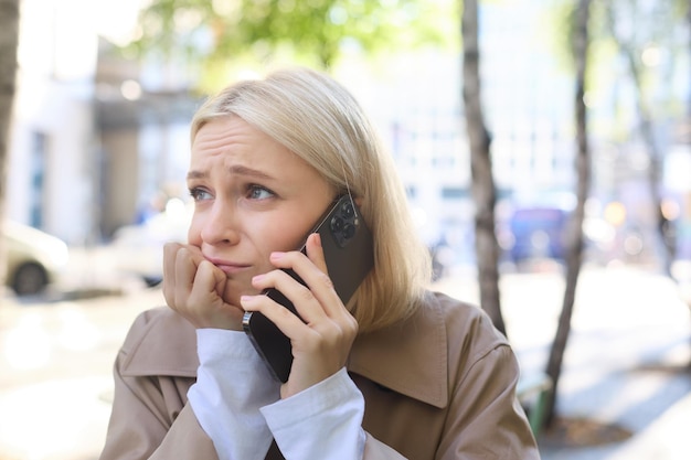 Gratis foto het beeld van een jonge, gestresste, overstuur vrouw die met een bezorgde gezichtsuitdrukking aan de mobiele telefoon praat, heeft