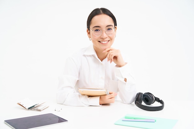 Het beeld van een jonge volwassen vrouw op de werkplek zit op de werkplek op kantoor met documentenhoofdtelefoons en ta