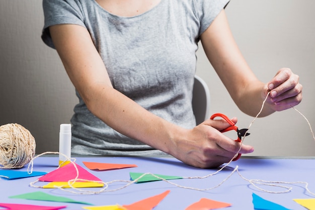 Het besnoeiingskoord van de vrouwenhand met schaar tijdens het maken van bunting