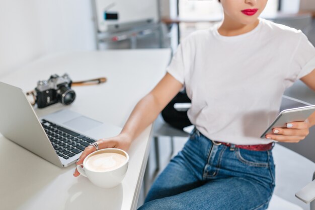 Het binnenportret van de close-up van glimlachend meisje in wit overhemd heeft koffiepauze in bureau
