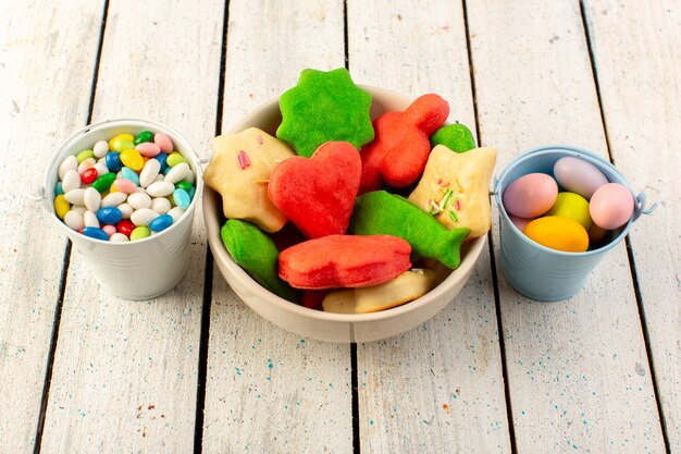 Het bovenaanzicht van kleurrijke heerlijke koekjes vormde veelkleurige veelkleurige binnenplaat met suikergoed